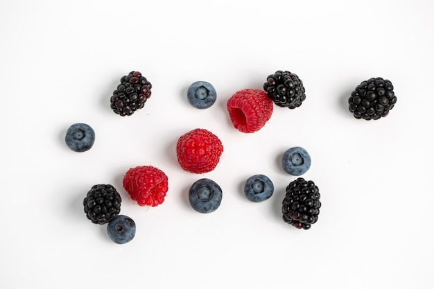 Mûres, framboises et bleuets isolés sur une surface blanche