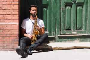Photo gratuite musicien assis et jouant du saxophone