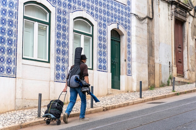 Musicien itinérant avec guitare sur le dos marchant dans les rues de lisbonne portugal