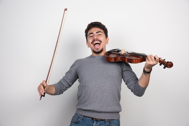 Le musicien joue du violon et a l'air inspiré et positif.