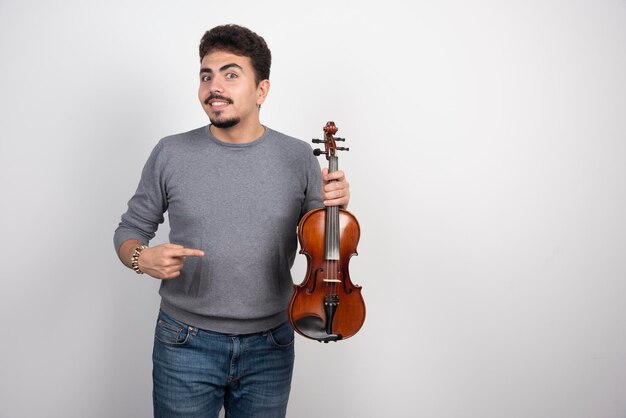 Le musicien joue du violon et a l'air inspiré et positif.