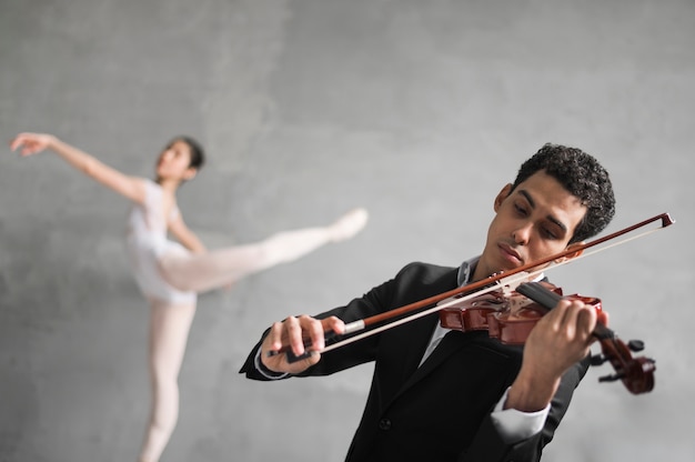 Photo gratuite un musicien joue du violon tout en dansant une ballerine défocalisée