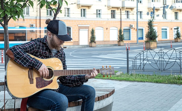 Le musicien masculin de rue joue la guitare acoustique