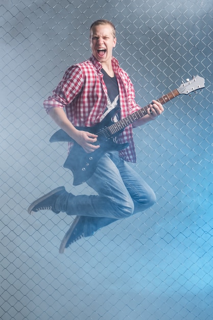 Photo gratuite la musique. jeune musicien avec une guitare en l'air