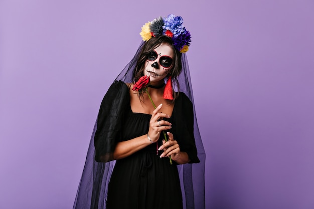 Mystérieuse Femme Mexicaine En Robe De Veuve Noire Posant Sur Un Mur Lilas. Photo De Fille Avec Une Couronne De Fleurs Et Des Boucles D'oreilles Lumineuses.