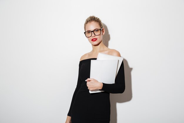 Mystery business woman in dress and eyeglasses holding documents