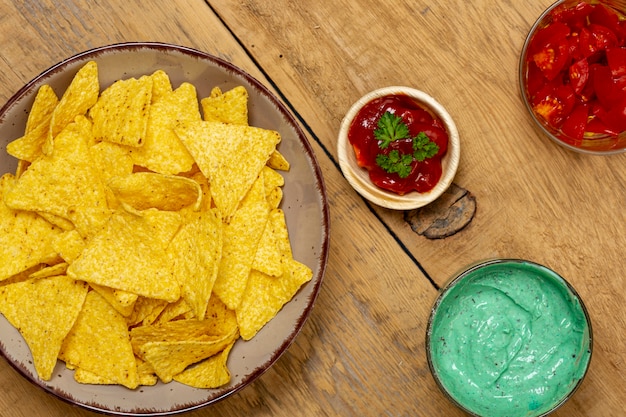 Photo gratuite nachos et diverses sauces organiques sur une table en bois posée