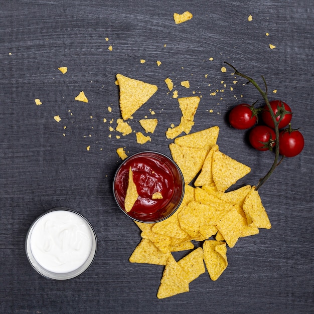 Photo gratuite nachos émiettés avec trempettes et tomates