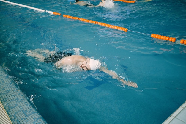 Nageur en casquette s'entraînant dans la piscine. Vue de dessus du côté de la piscine.