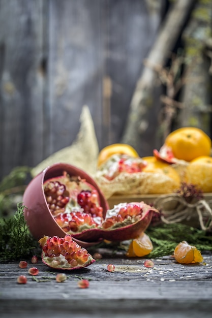 Photo gratuite nature morte aux mandarines et grenade sur bois