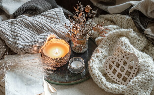 Nature morte avec des bougies dans des chandeliers, des détails de décoration et des articles tricotés.