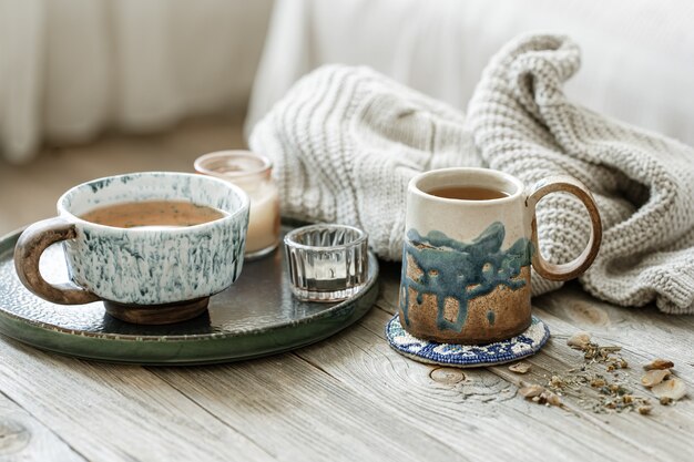 Nature morte confortable avec des tasses en céramique avec du thé et un élément tricoté.