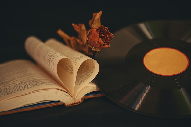 Nature morte avec des livres en forme de coeur, des fleurs séchées et un vieux CD.