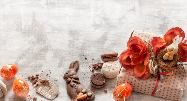 Nature morte de Pâques avec des cadeaux et des bonbons sur bois.