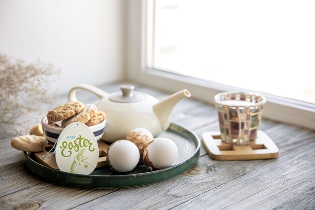 Nature morte de Pâques faite maison avec du thé et des biscuits sur le rebord de la fenêtre le matin