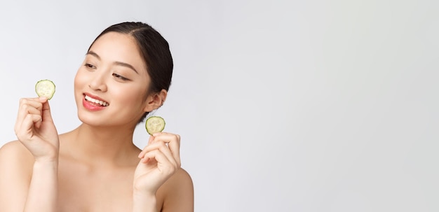 Naturel fait maison concombre frais coussinets pour les yeux masques faciaux femme asiatique tenant des coussinets de concombre et sourire se détendre avec naturel fait maison