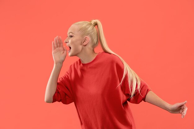 Ne manquez pas. Jeune femme décontractée criant. Crier. Femme émotive qui pleure criant sur fond de studio de corail. Portrait de femme demi-longueur. Émotions humaines, concept d'expression faciale. Couleurs tendance