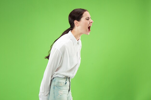 Ne manquez pas. Jeune femme décontractée criant. Crier. Femme émotive qui pleure crier sur fond de studio vert. Portrait de femme demi-longueur. Émotions humaines, concept d'expression faciale. Couleurs tendance