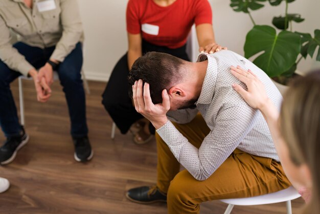 Ne vous inquiétez pas, tout ira bien. Membres d'un AA ou d'un groupe de soutien réconfortant un homme hispanique triste et offrant des conseils de santé mentale