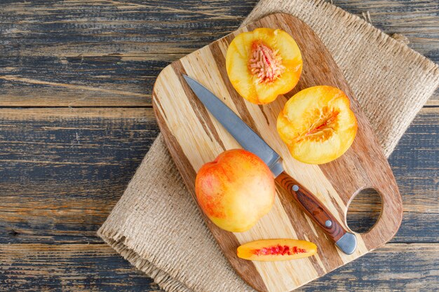 Nectarines avec couteau, planche à découper à plat sur bois et morceau de sac