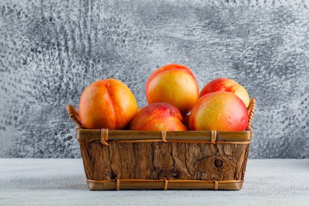 Nectarines dans une vue latérale du panier sur un mur sale