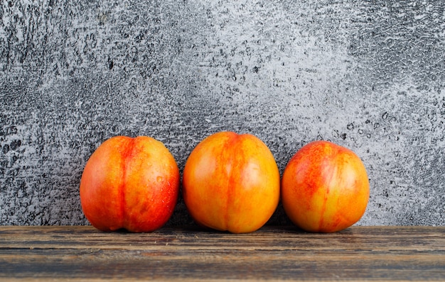 Photo gratuite nectarines sur mur en bois et grungy. vue de côté.