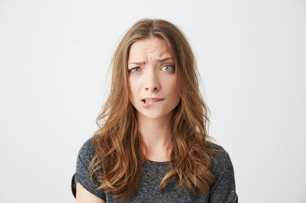 Nerveuse jeune belle fille fronçant les sourcils mordant la lèvre.