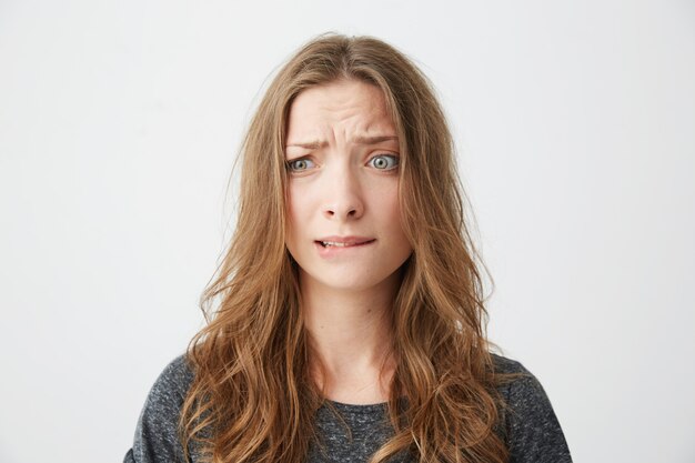 Nerveuse jeune belle fille fronçant les sourcils mordant la lèvre.