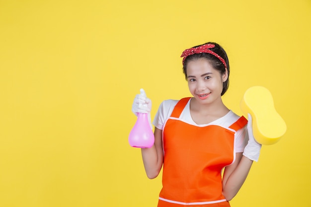 Nettoyage . Une belle femme avec un appareil de nettoyage sur un jaune.