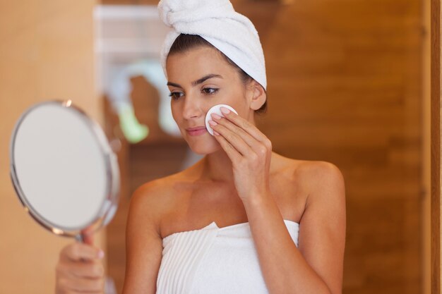 Nettoyage du visage de femme dans la salle de bain