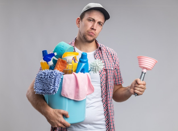 Nettoyant jeune homme confiant portant une casquette tenant un seau d'outils de nettoyage avec piston isolé sur fond blanc