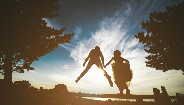 Newlyweds sautant dans le coucher du soleil