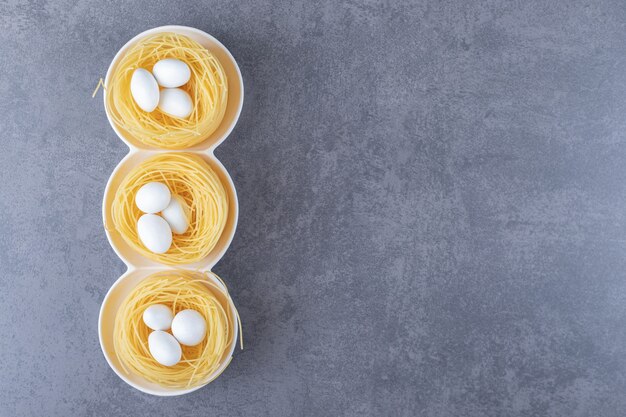 Nids de nouilles aux œufs avec des bonbons blancs dans des bols.