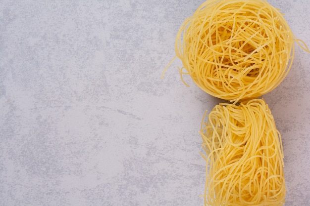 Photo gratuite les nids de spaghetti non cuits sur la surface de la pierre