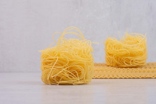 Photo gratuite nids de spaghettis crus et pâtes sur table en marbre.