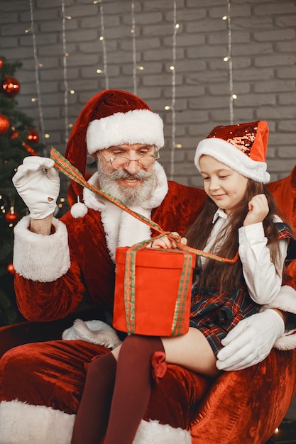 Photo gratuite noël, enfant et cadeaux. le père noël a apporté des cadeaux à l'enfant. joyeuse petite fille étreignant le père noël.