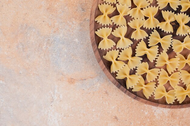 Noeud papillon pâtes sur plaque en bois sur fond de marbre. Photo de haute qualité