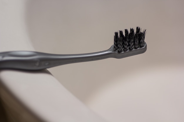 Noir une brosse à dents placée dans une salle de bain derrière un fond blanc