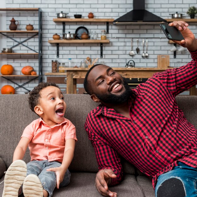 Noir joyeux père et fils prenant selfie