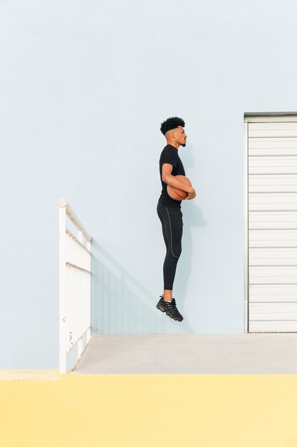 Noir sportif sautant avec basket au porche