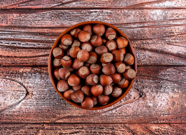 Noisettes décortiquées dans un bol brun sur une table en bois. mise à plat.