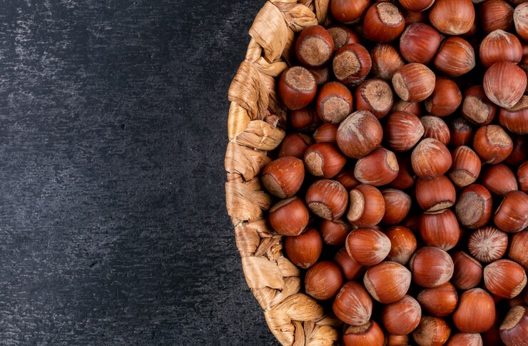 Photo gratuit noisettes décortiquées dans un panier en osier sur une table en pierre noire. fermer.