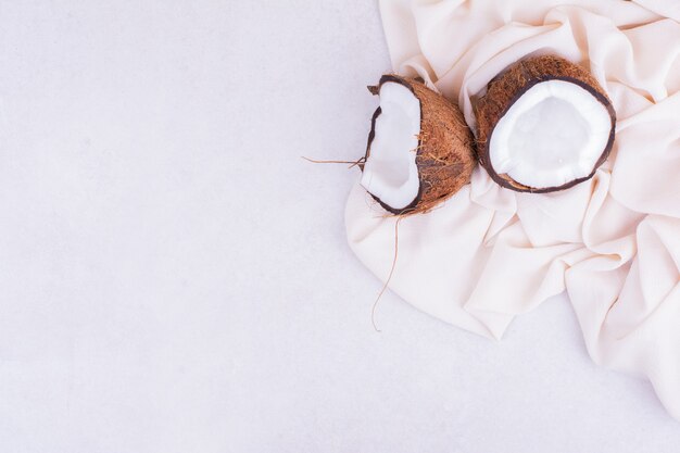 Noix de coco cassée en deux morceaux sur une nappe beige