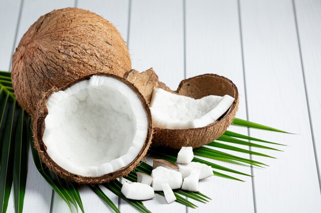 Noix de coco fraîches mises sur fond de bois blanc