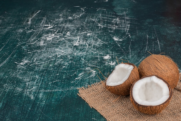 Photo gratuite noix de coco à moitié coupées et entières sur drap de laine