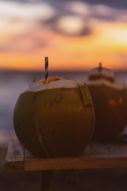 Noix de coco avec une paille sur fond de coucher de soleil, vie tropicale