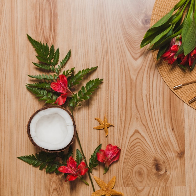 Noix de coco, plantes, fleurs et chapeau