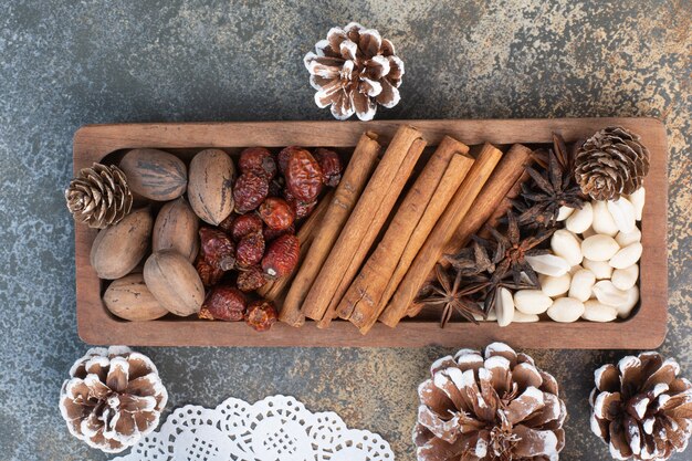 Noix mélangées avec des bâtons de cannelle et des fruits secs sur une plaque en bois. Photo de haute qualité