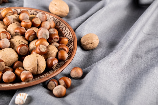 Noix mélangées dans une assiette de poterie décorative isolée sur une nappe bleue