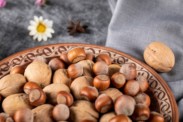 Noix et noix dans un bol en poterie avec marguerite autour